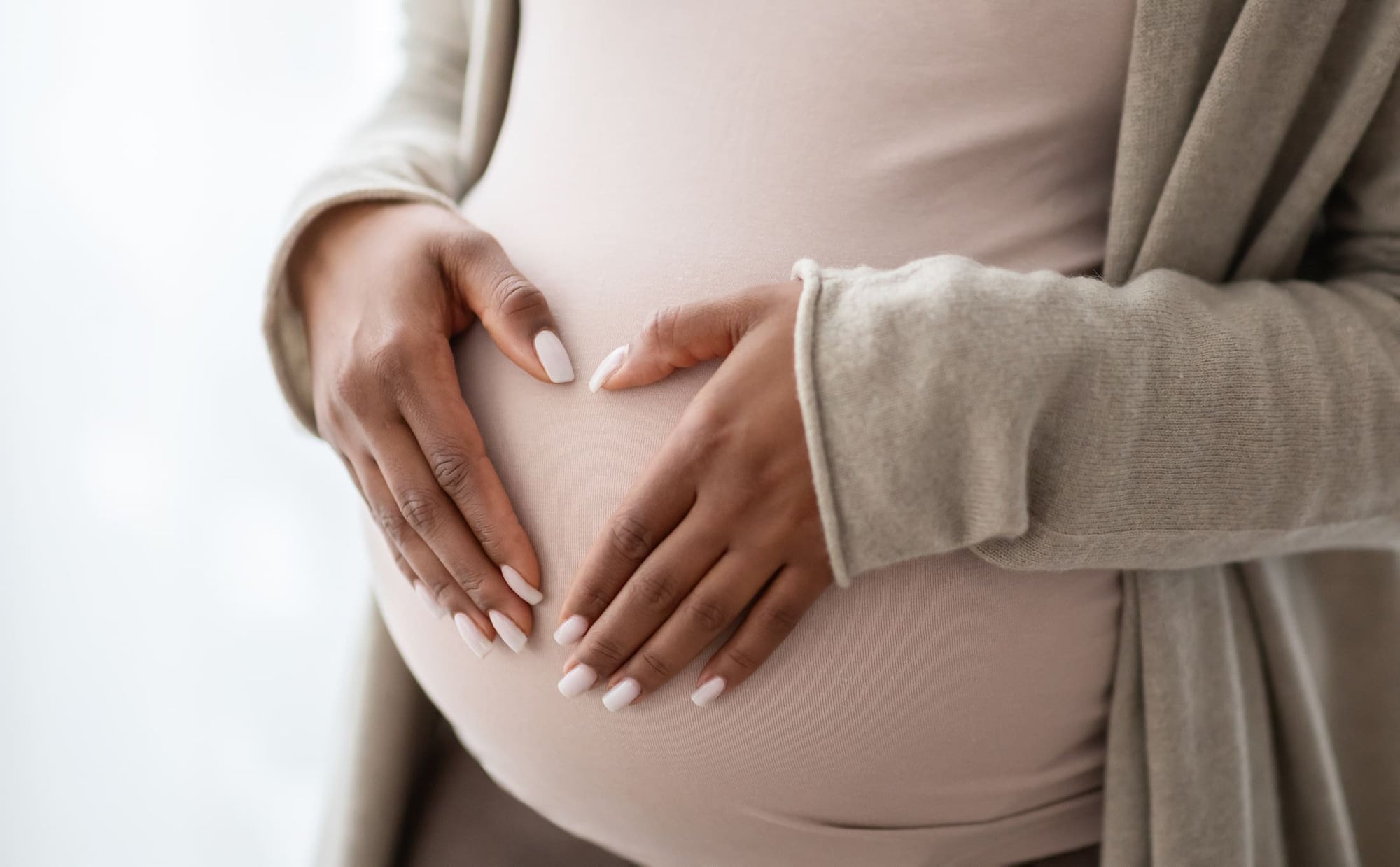 Mulher grávida com as mãos formando um coração sobre a barriga, ilustrando cuidados com a pele na gravidez.