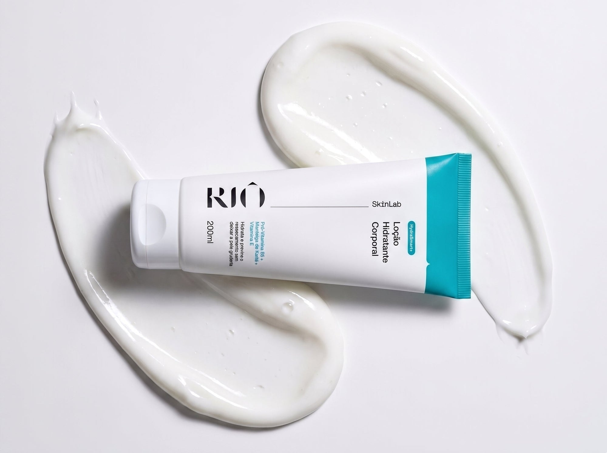Bisnaga da Loção Hidratante Corporal Riô SkinLab 200ml sobre respingos do creme branco em fundo claro.