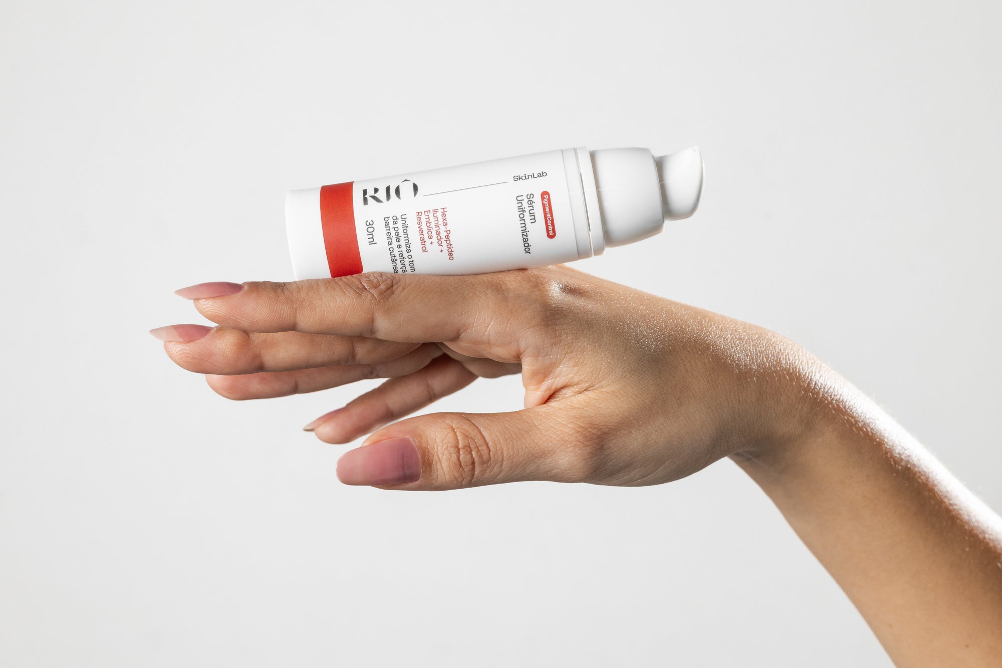 Frasco do Sérum Uniformizador PigmentControl da Riô SkinLab apoiado sobre a mão.